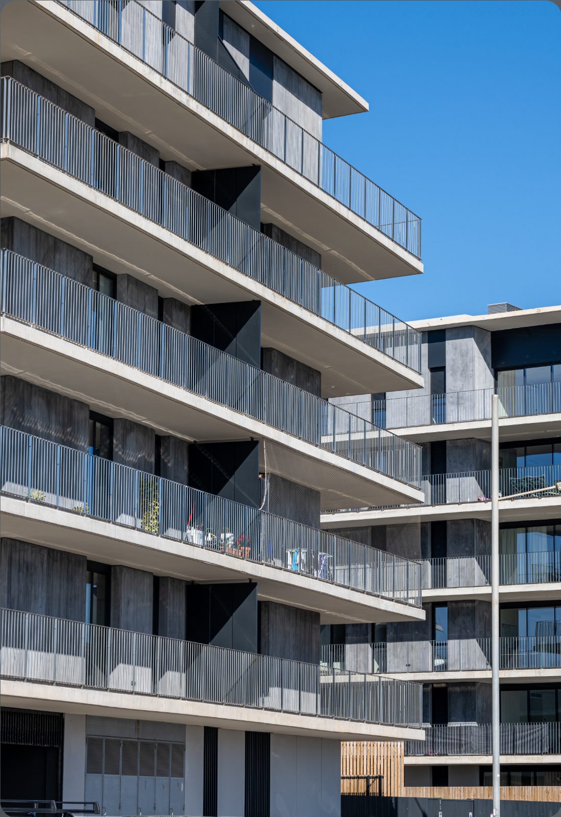A modern balconied apartment block against a clear sky
