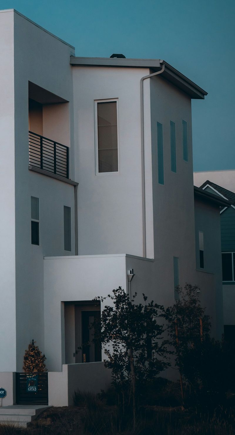 A modern white stucco townhome against an evening sky