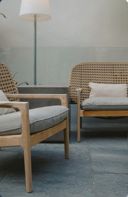 Two wood and rattan lounge chairs on a stone patio
